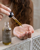 Person using a dropper to apply a liquid from a GUADA bottle onto their palm.