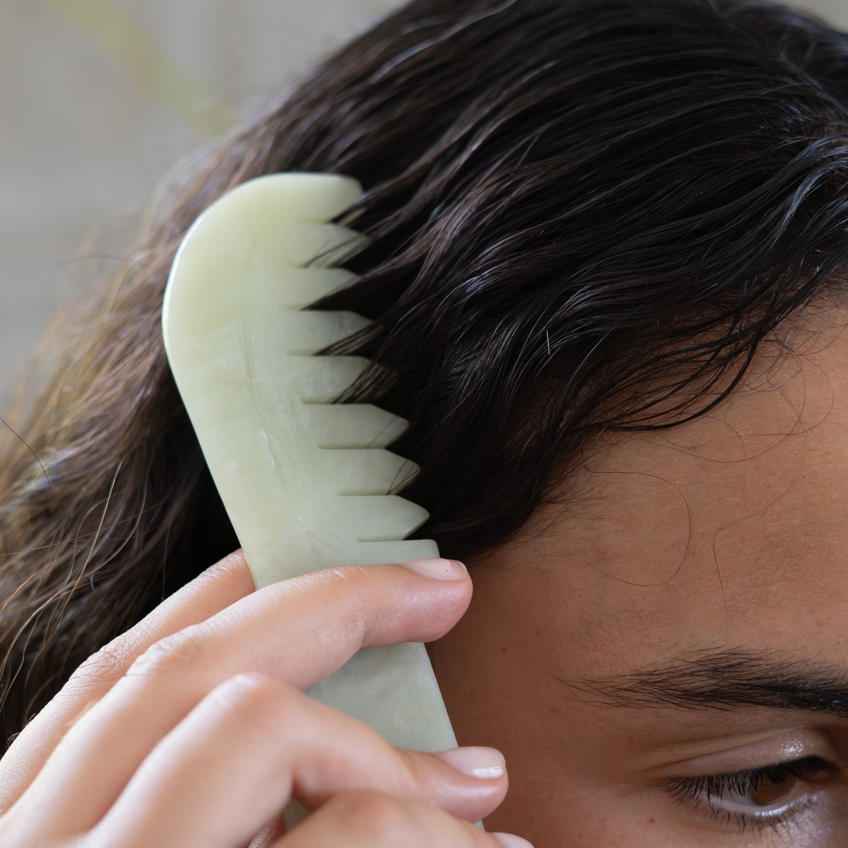 Jade scalp comb gliding through hair